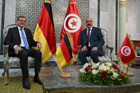 Johann Wadephul seated with Tunisian officials, German and Tunisian flags in the background