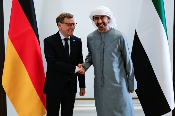 Johann Wadephul shaking hands with an Emirati official in front of German and UAE flags