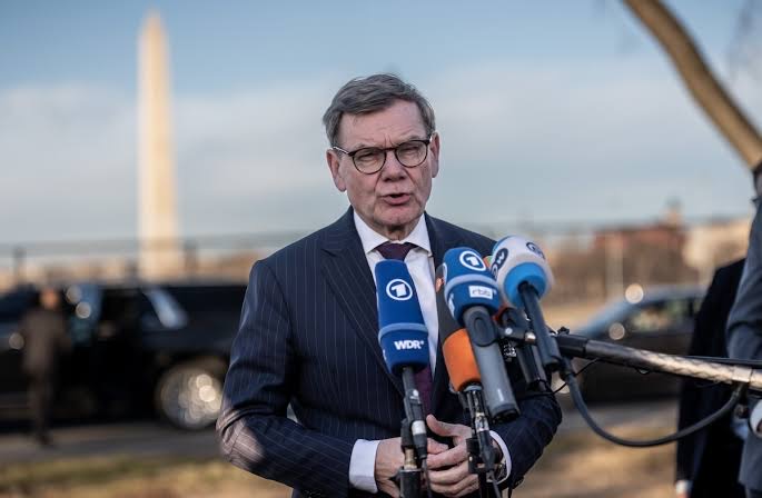 Johann Wadephul giving a press statement outdoors in Washington, with the Washington Monument in the background