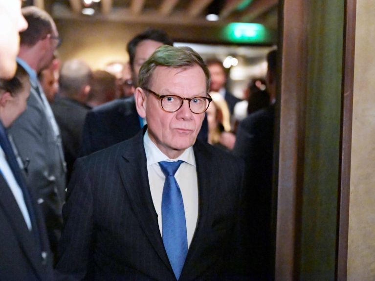 Johann Wadephul in a dark suit and blue tie among other guests in a crowded room
